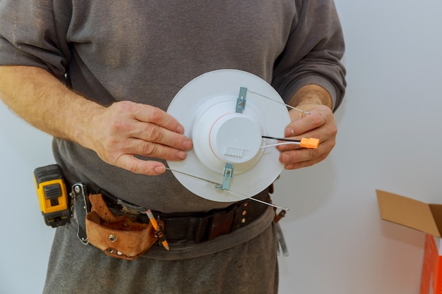 Homem está instalando luz elétrica no teto substituindo trabalhos de reparação no apartamento.