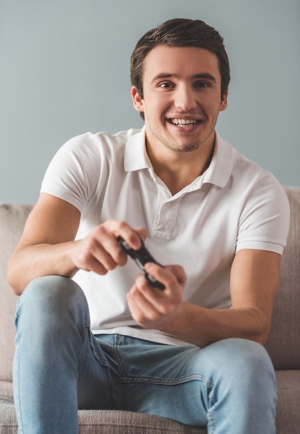 Homem está jogando videogame e sorrindo