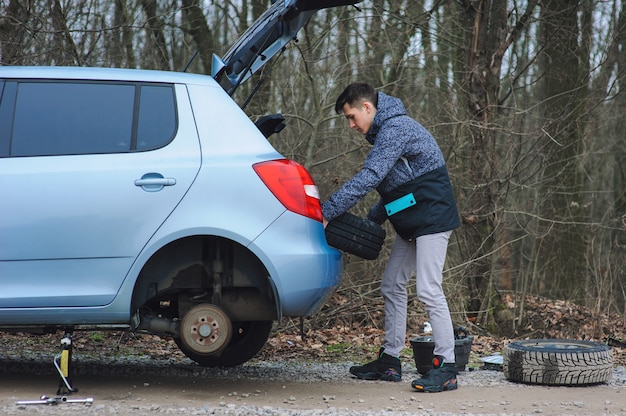 Homem está trocando pneu com roda no carro