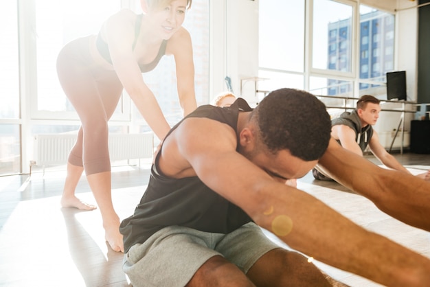 Homem, esticar e malhar com o treinador no estúdio de yoga