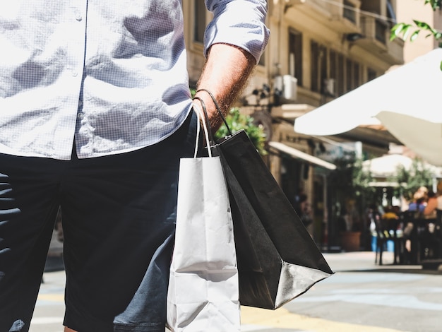 Homem estiloso com duas malas na rua no verão, dia ensolarado. Conceito de estilo, moda e beleza