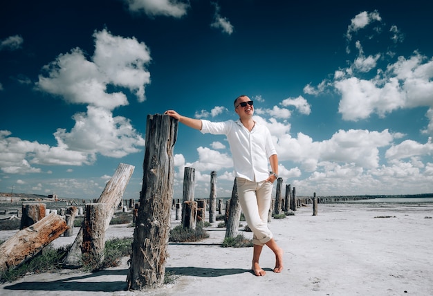 Homem estiloso com óculos de sol posando na praia