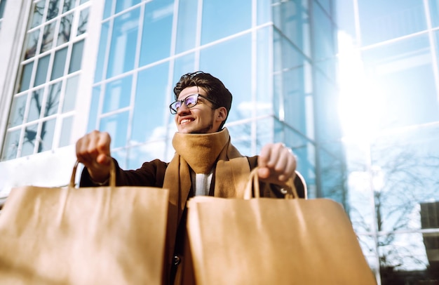 Homem estiloso com pacotes de papel após as compras Conceito de estilo de vida consumista de venda