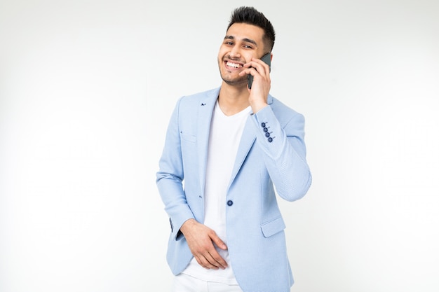 Homem estiloso em uma jaqueta falando ao telefone em um estúdio branco