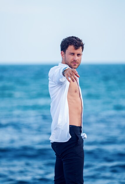 Homem estiloso estendendo a mão na praia