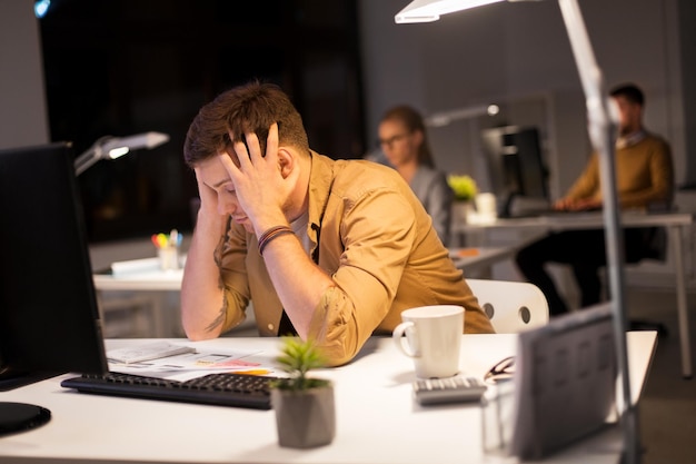 Foto homem estressado no monitor do computador no escritório à noite