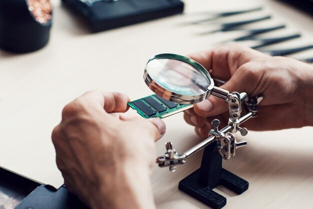 Homem estudando micro circuito em oficina