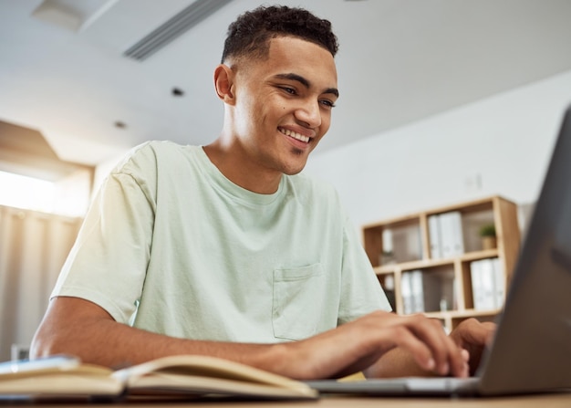 Foto homem estudante e digitando no laptop com educação e notas escrevendo relatório para a universidade e feliz estudando em casa produtividade on-line e conhecimento crescimento acadêmico e desenvolvimento para a faculdade