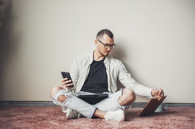 Homem estudante usando telefone inteligente móvel olhando para seu livro de navegação aplicativo de internet no smartp