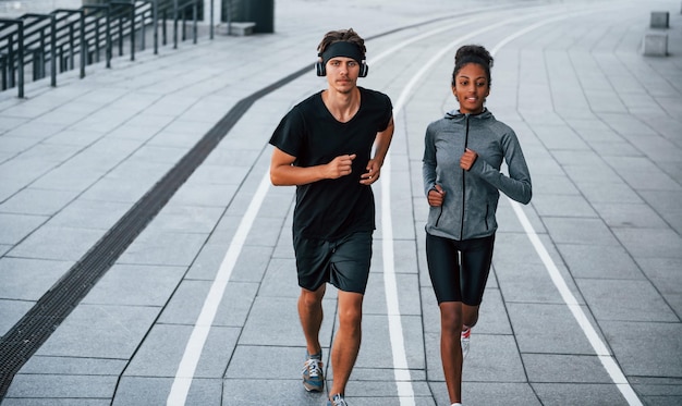 Homem europeu e mulher afro-americana em roupas esportivas treinam juntos