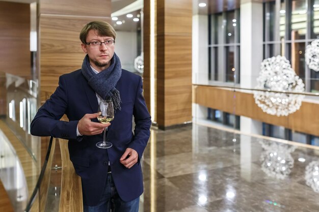 Homem europeu elegante em copos com cachecol descansando com copo de vinho