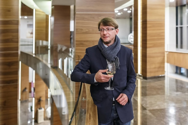 Homem europeu elegante em copos com cachecol descansando com copo de vinho