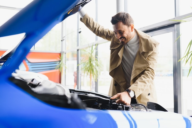 Foto homem examinando o motor de um automóvel novo na concessionária, olhando sob o capô