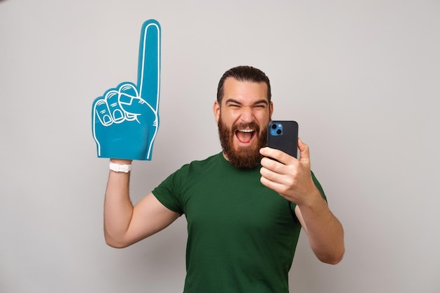 Homem excitado está assistindo streaming online de um jogo de esportes no telefone