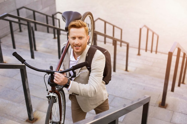 Homem excitado mantendo uma bicicleta por cima do ombro Foto Premium