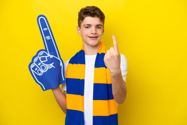 Homem fã de esportes adolescente isolado em fundo amarelo, fazendo o gesto de chegada