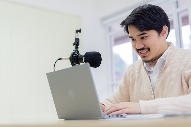 Homem fala na produção do conjunto de microfones à mesa no estúdio de recodificação para transmissão de podcast