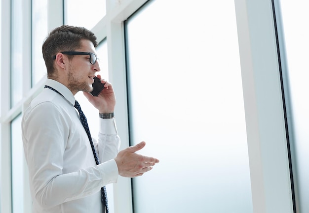 Homem falando ao telefone e sorrindo no escritório