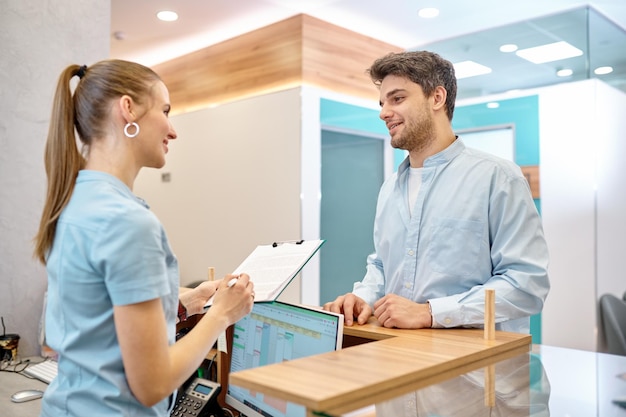 Homem falando com recepcionista profissional na clínica