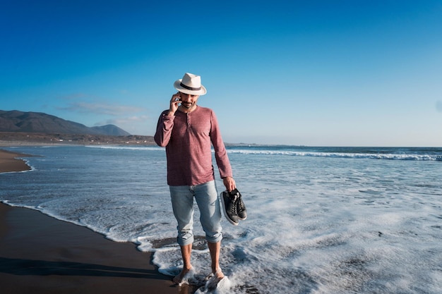 Homem falando no celular na praia ao pôr do sol