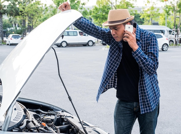 Foto homem falando por telefone inteligente enquanto está de pé perto de um carro danificado