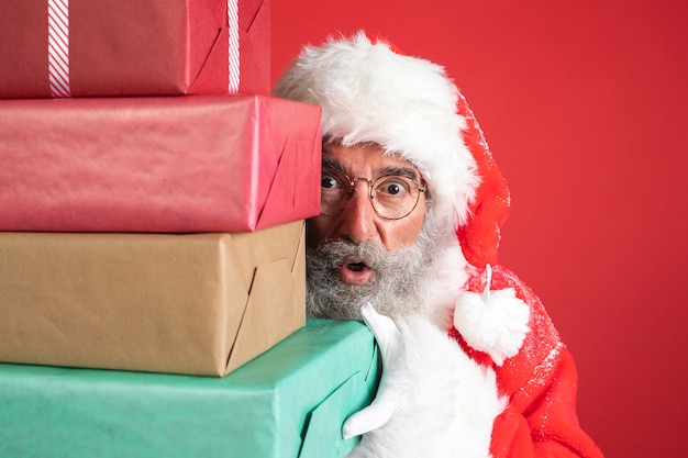 Foto homem fantasiado de papai noel segurando presentes