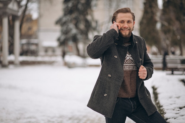 Homem farpado falando ao telefone na rua no inverno