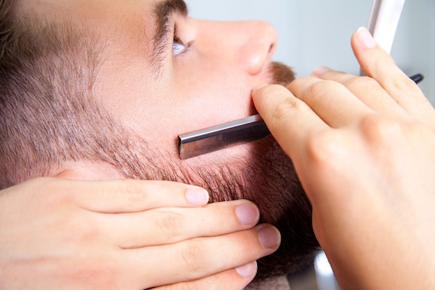 Homem fazendo a barba na barbearia.