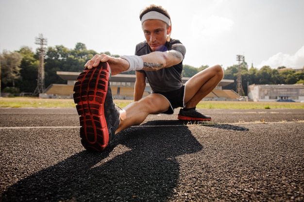 Homem fazendo alongamento na pista de corrida