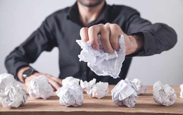 Homem fazendo bolas de papel amassado em cima da mesa.