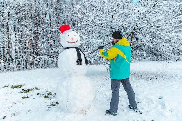 Homem fazendo boneco de neve ao ar livre no conceito de parque de inverno gelado