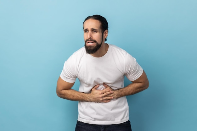 Homem fazendo careta e sofrendo de dor na barriga desconforto abdominal grave