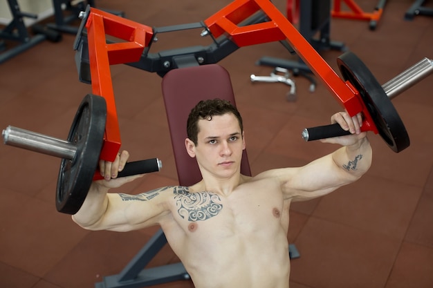 Homem fazendo exercícios de peito na máquina de supino vertical