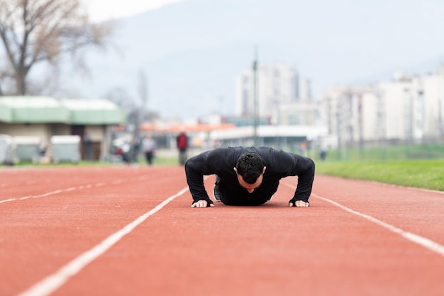 Homem fazendo flexões na pista