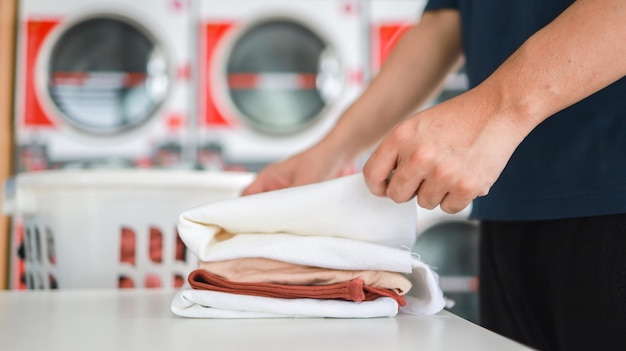 Homem fazendo lavagem segurando cesta com roupa suja da máquina de lavar no conceito de roupas de lavanderia de loja pública