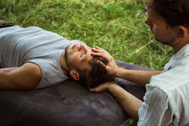 Homem fazendo massagem osteopática de cabeça e pescoço na natureza 4