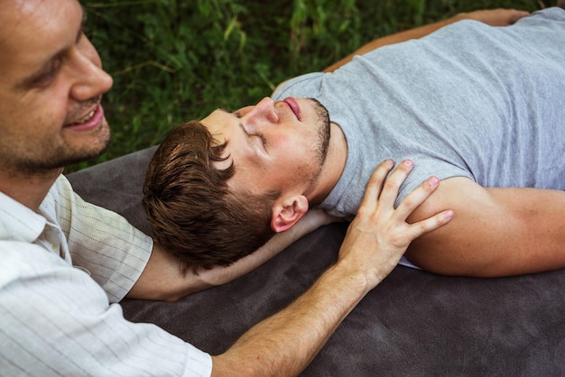 Homem fazendo massagem osteopática no pescoço e ombros para um cara na natureza