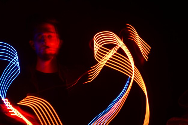 Foto homem fazendo pintura de luz colorida no escuro à noite