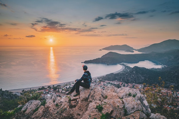 Homem feliz admirando a vista de um pôr do sol cênico sobre a cidade de Oludeniz, na Turquia, pontos turísticos da Via Lícia