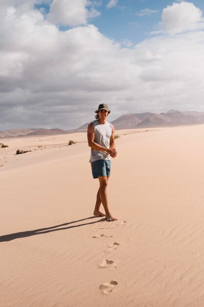Homem feliz andando no deserto de Fuerteventura no verão durante uma viagem de férias
