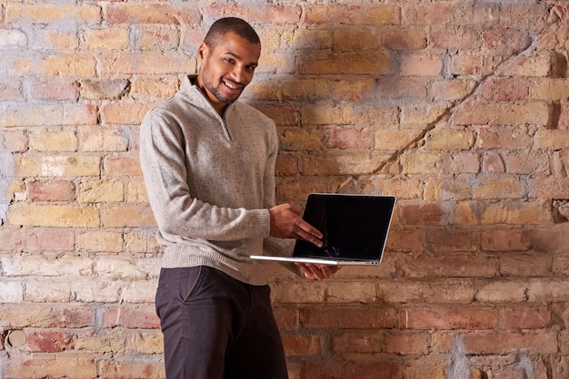 Homem feliz, apontando para um laptop