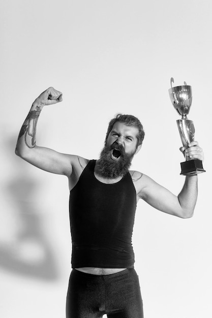 Foto homem feliz barbudo detém a taça de campeão de ouro em fundo cinza