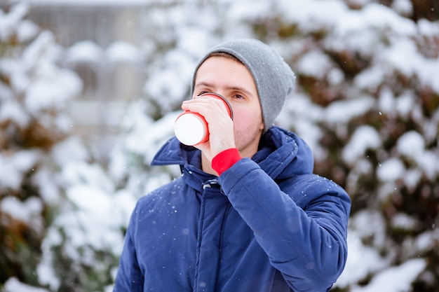 Homem feliz bebendo café ao ar livre no inverno