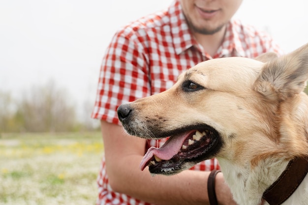 Homem feliz brinca com cão pastor de raça mista na grama verde