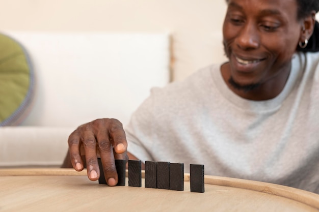 Foto homem feliz brincando com peças de dominó