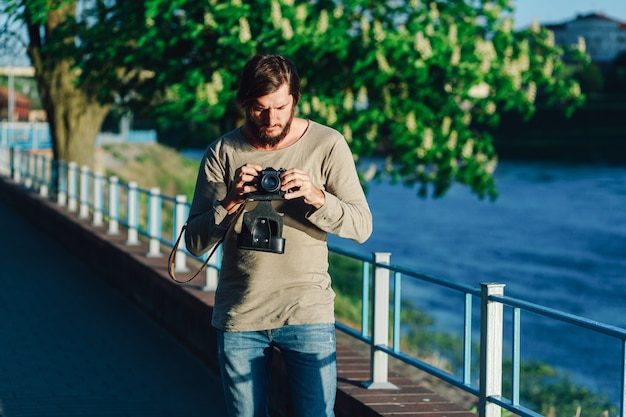 Homem feliz casual hipster fazendo foto usando a câmera retro ao ar livre no parque