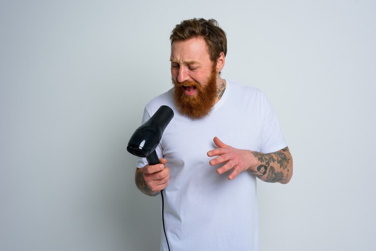 Foto homem feliz com barba usando secador de cabelo como microfone e dança