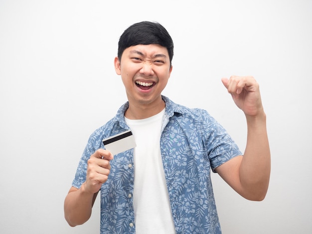 Homem feliz com cartão de crédito na mão e punho no sucesso