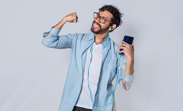 Homem feliz com fones de ouvido segurando um telefone celular e comemorando um cara com seu smartphone comemorando a vitória