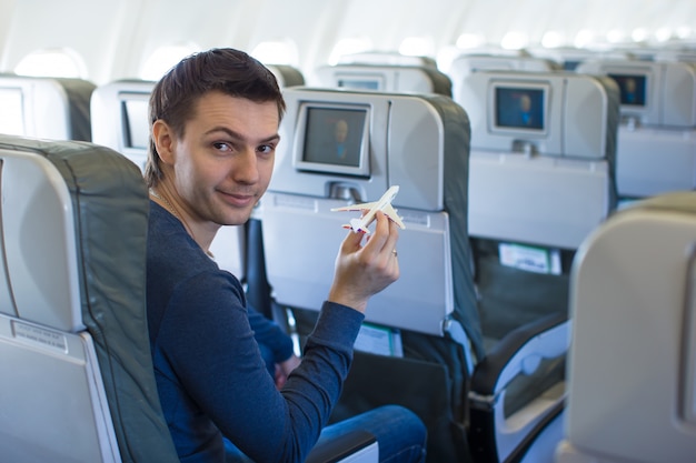 Foto homem feliz com pequeno modelo de avião dentro de uma aeronave grande